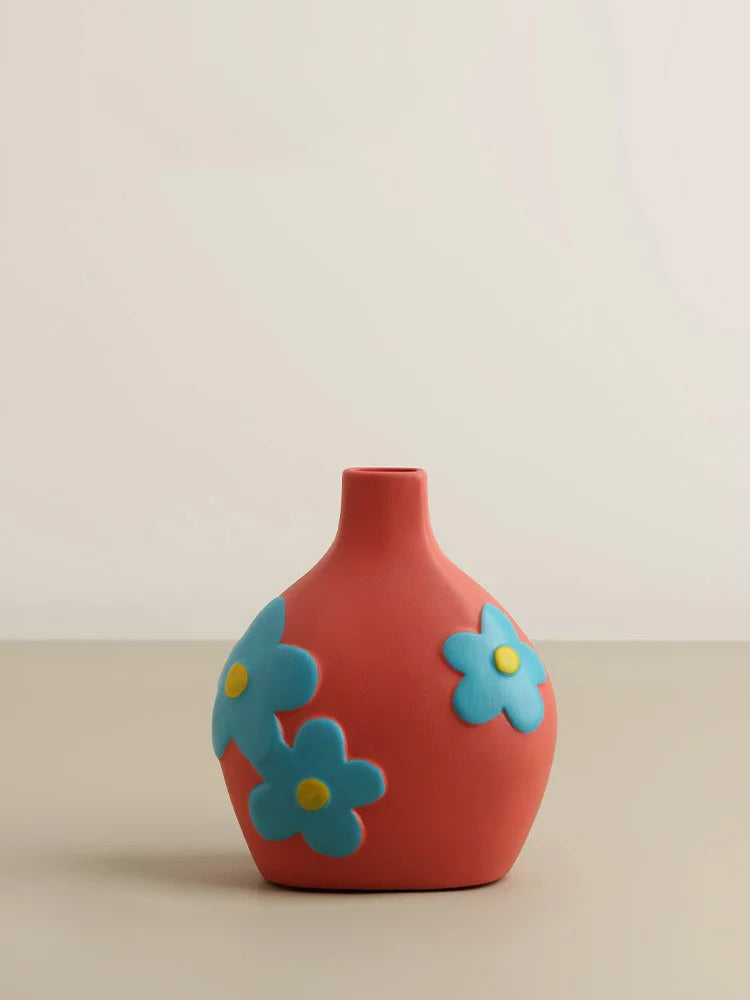 Red vase with blue flower designs on a beige background