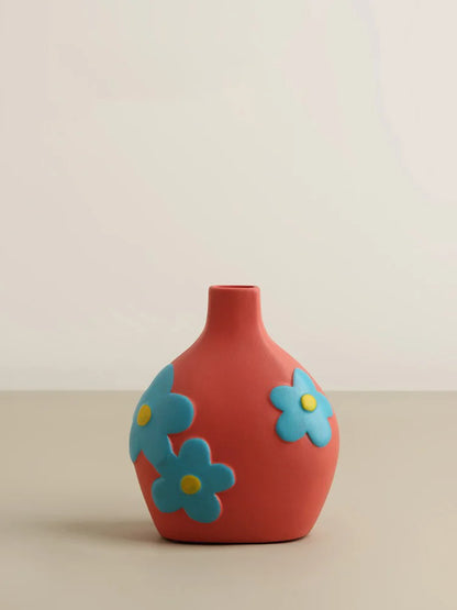 Red vase with blue flower designs on a beige background