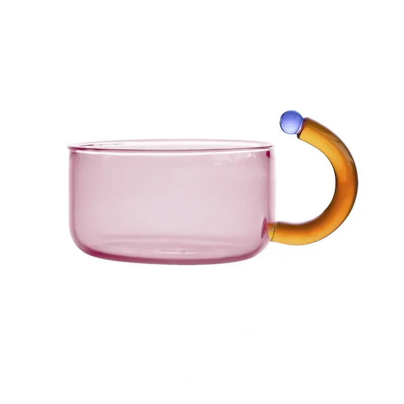 Pink glass mug with a multicolored handle on a white background