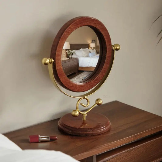 Round wooden mirror on a stand with a gold frame, placed on a wooden surface.