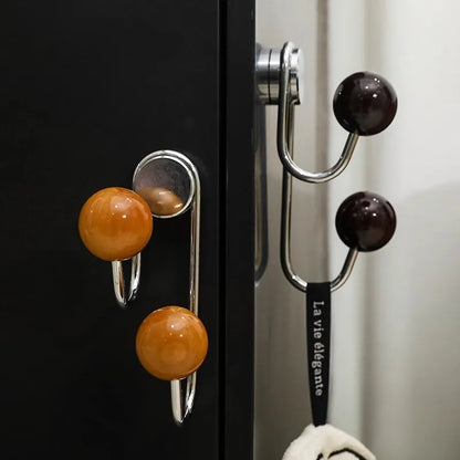 Decorative hooks with spherical ends attached to a black surface and white wall.