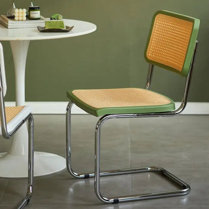 Modern chair with green cushioned seat and backrest in a minimalistic setting.