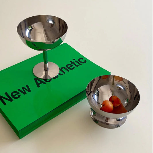 Two metallic bowls on a white surface with a green book titled 'New Aesthetic'.