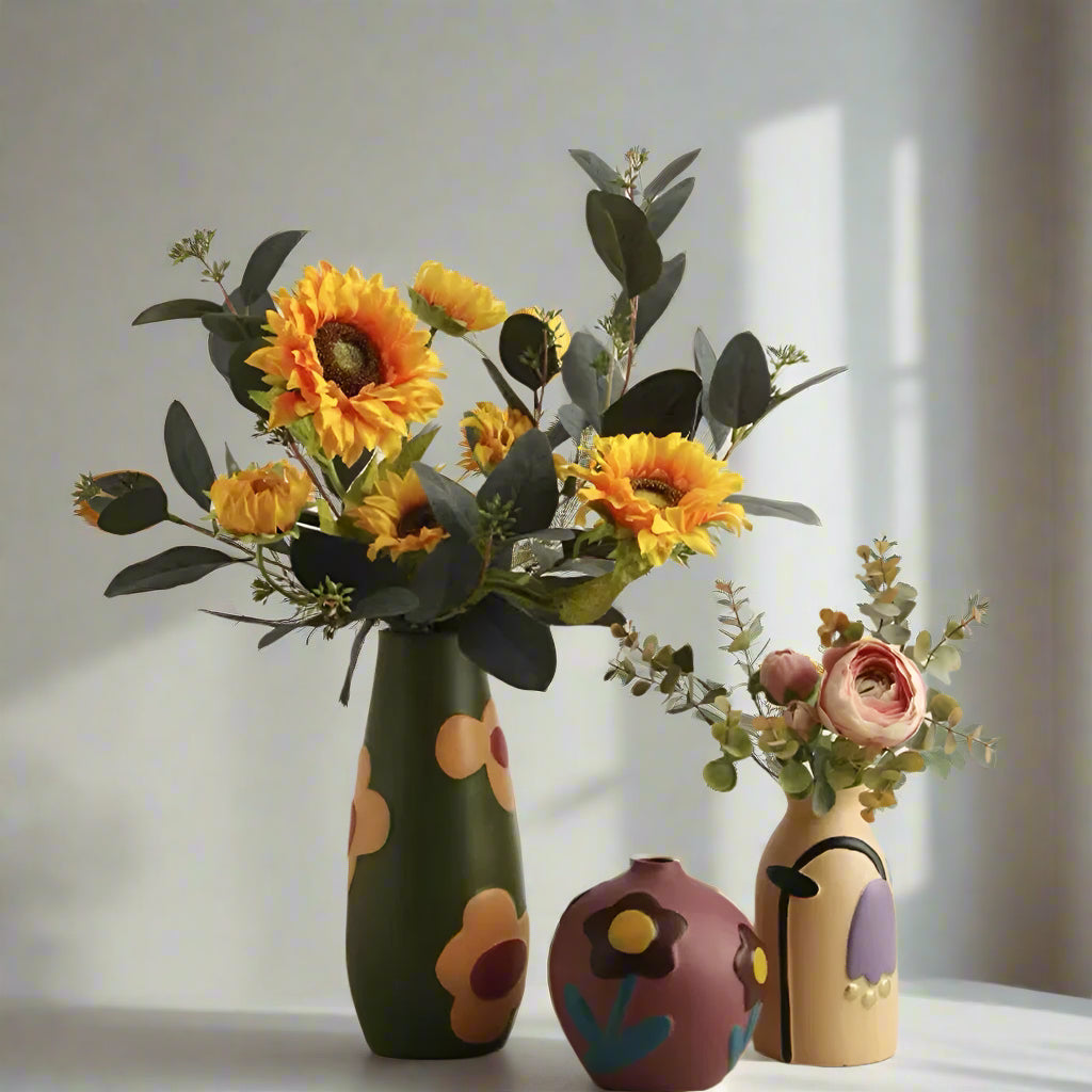 Three colorful vases with floral arrangements on a plain background