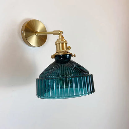 Wall-mounted lamp with brass fixture and blue glass shade on a white background