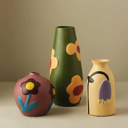 Three colorful ceramic vases with floral designs on a beige background