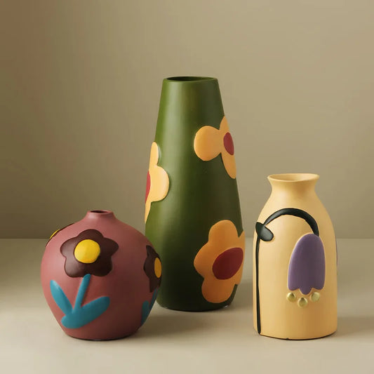 Three colorful ceramic vases with floral designs on a beige background