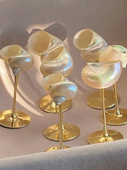 Set of decorative items with iridescent shells on gold stands against a neutral background