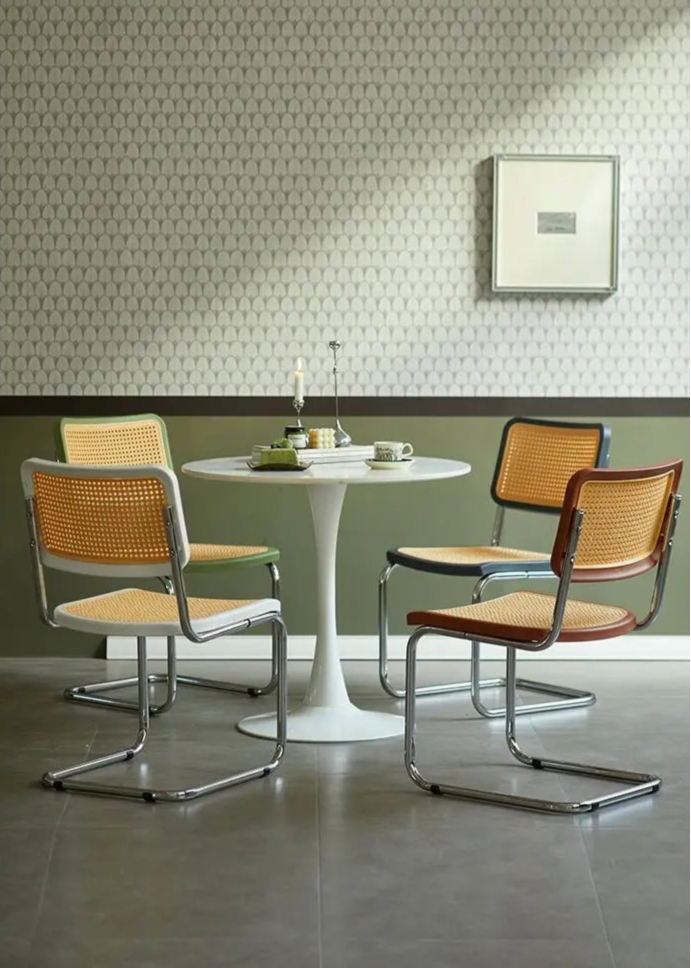 Dining area with a round table and four chairs against a patterned wall.