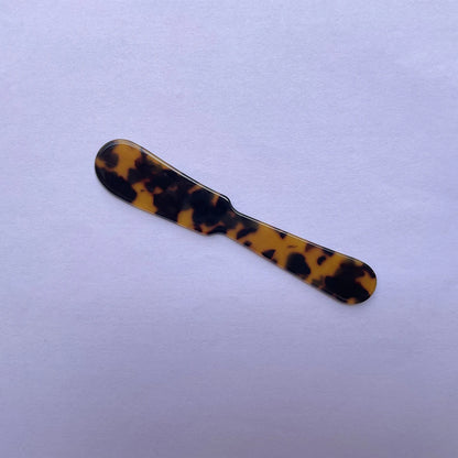Butter knife with tortoiseshell pattern on a light purple background