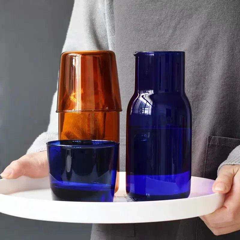 Person holding a tray with two blue glass carafes.