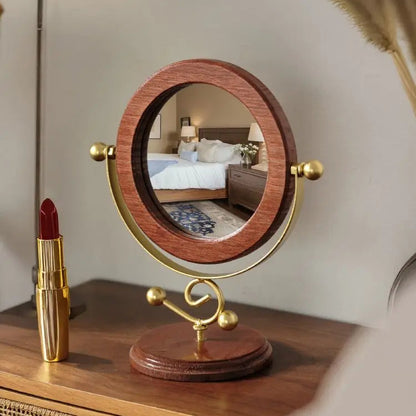 Wooden and gold vanity mirror on a dresser with a red lipstick next to it.
