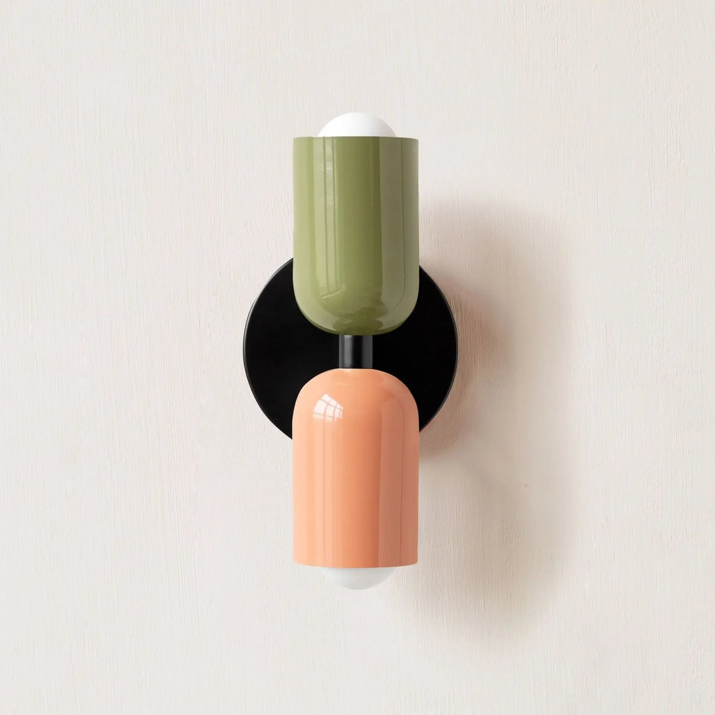 Wall-mounted light fixture with green and peach-colored design on a white background