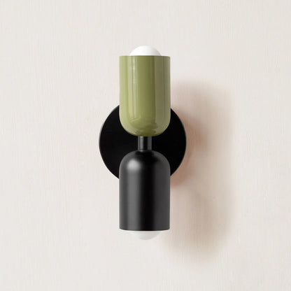 Wall-mounted lamp with green glass shade and black base on a light beige background