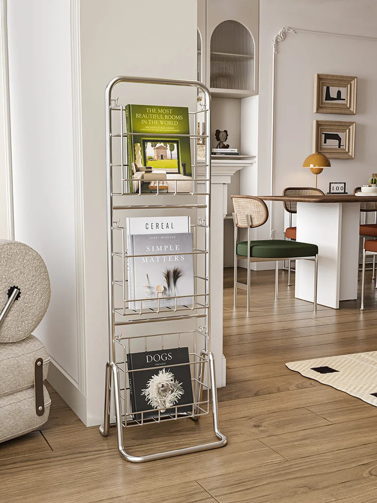 Metal magazine rack with books on a wooden floor in a living room.