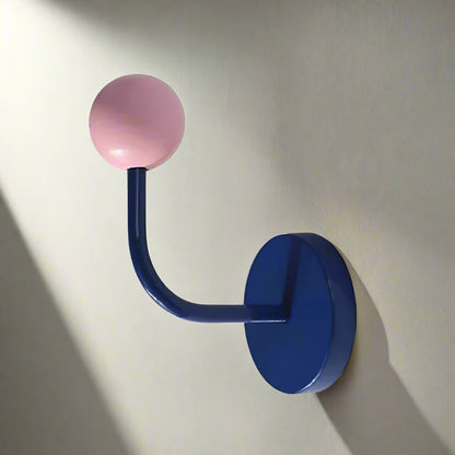 Wall hook with pink spherical end on a white background