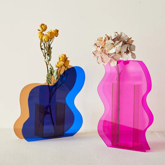 A blue and a pink asymmetrical vase on a white backdrop