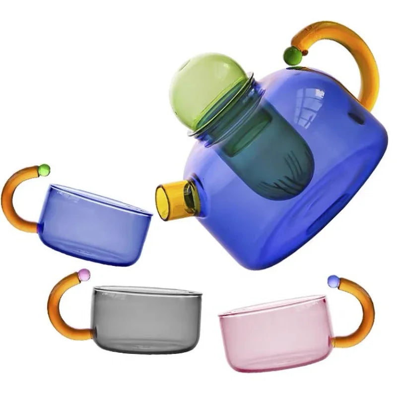 Colorful glass teapot and mugs with orange handles on a white background