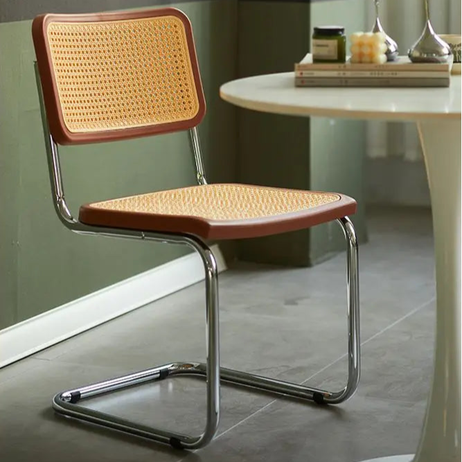 Chair with wicker seat and backrest in a room with a table and decor.