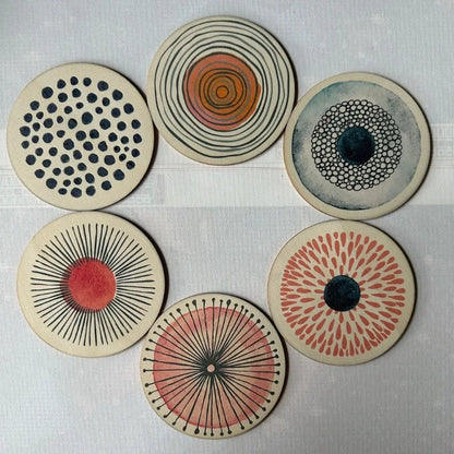 Set of six circular coasters with various patterns on a light gray background