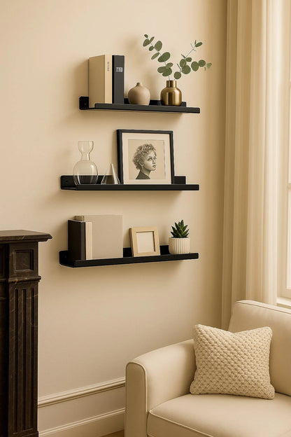 Decorative wall shelves with books, a clock, and a framed picture in a room with a beige sofa and window.