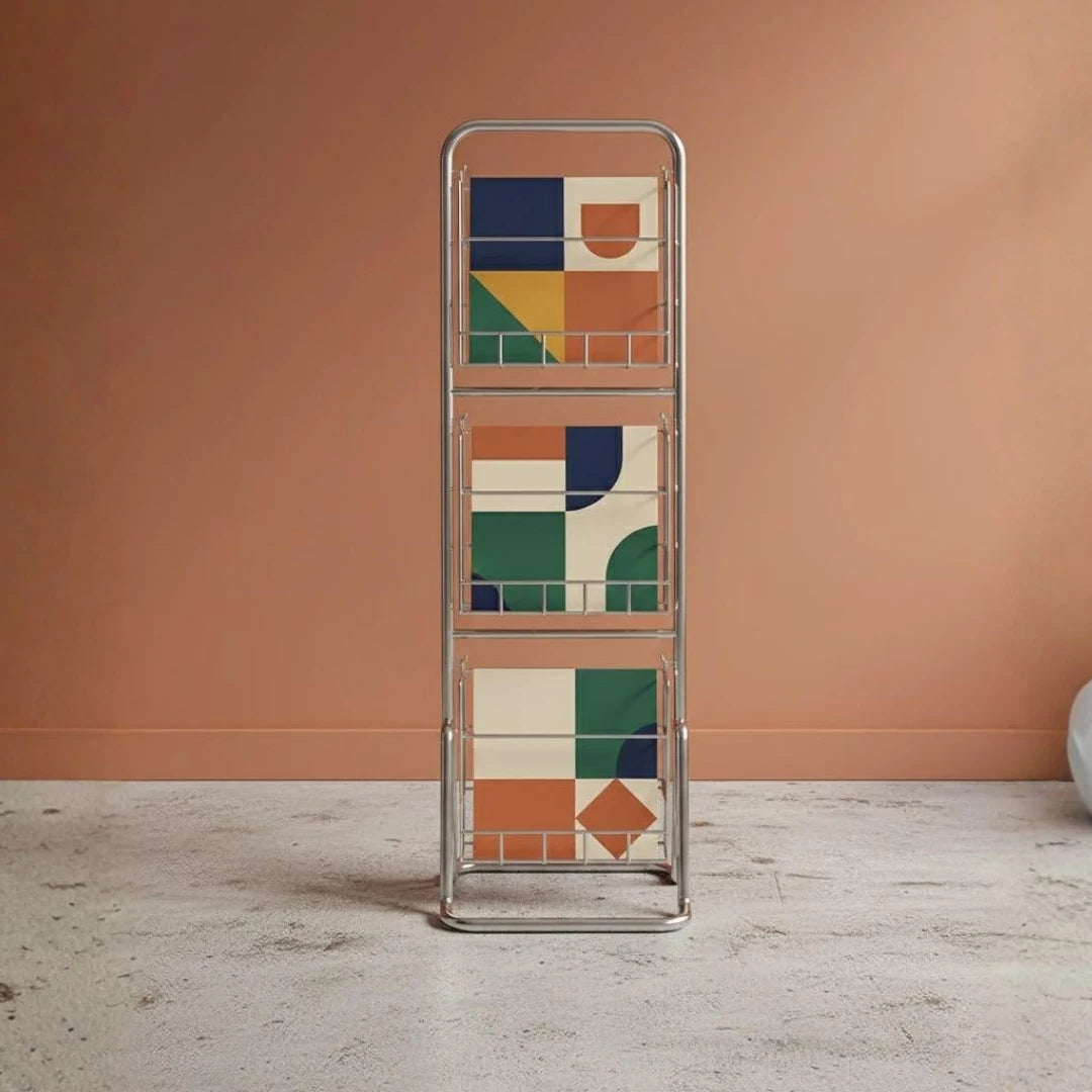 Metallic magazine rack with geometric pattern against a peach-colored wall.