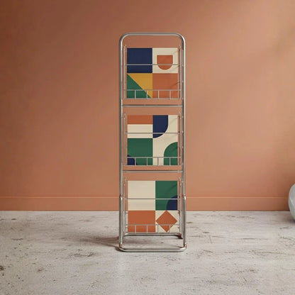 Metallic magazine rack with geometric pattern against a peach-colored wall.