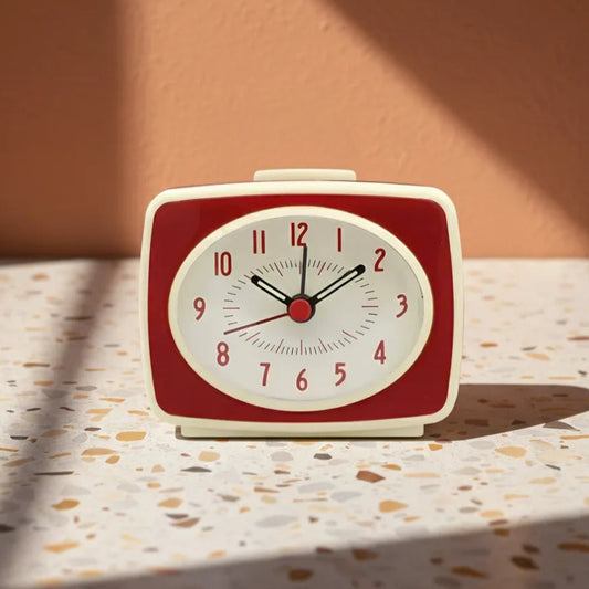 Red and white alarm clock on a textured surface with a warm background