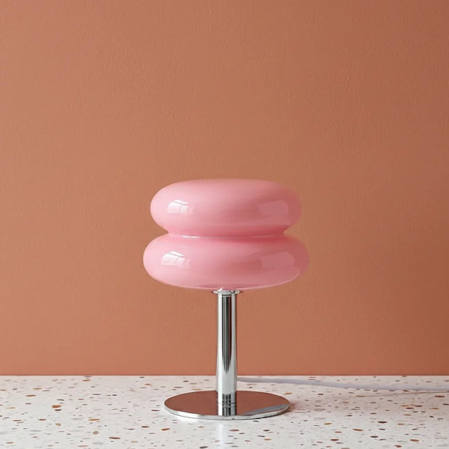 Pink stool with a metallic base on a terrazzo surface against a peach wall.