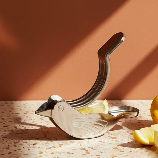 Metallic lemon squeezer with lemons on a terrazzo countertop