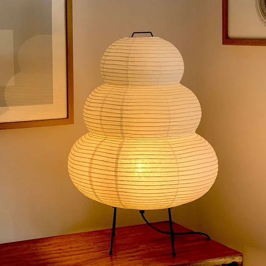 Textured lamp on a wooden surface with framed pictures in the background