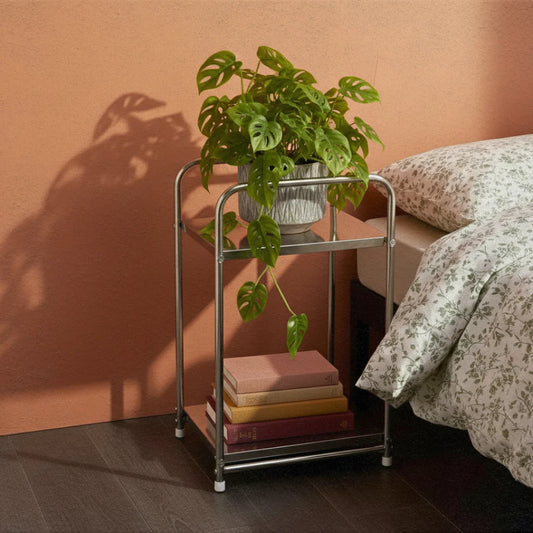 Metal trolley with books and a plant against a peach-colored wall.