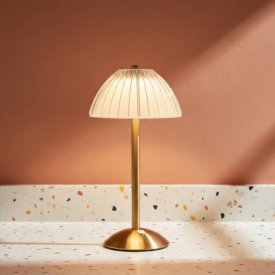 A glass fluted table lamp on a terazzo work surface omitting a warm light.