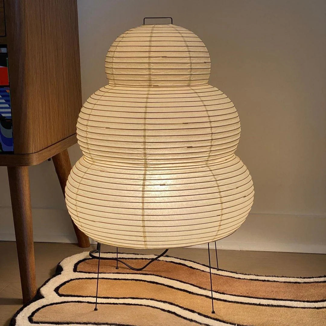 Woven lamp on a patterned rug with a wooden cabinet in the background