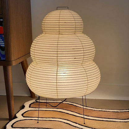 Woven lamp on a patterned rug with a wooden cabinet in the background