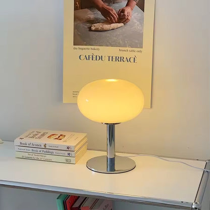 Yellow table lamp on a shelf with books and a poster in the background