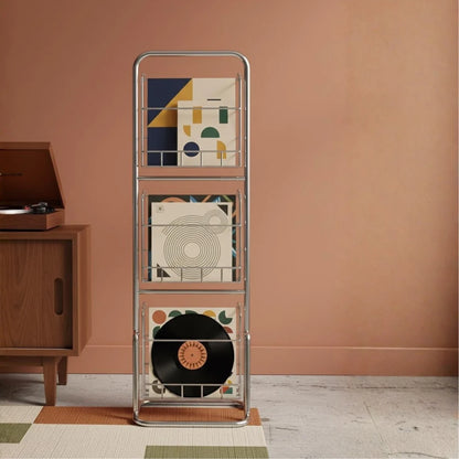 Record player with a metal stand displaying vinyl records against a pink wall.