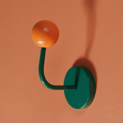Green and orange wall hook on a peach-colored background