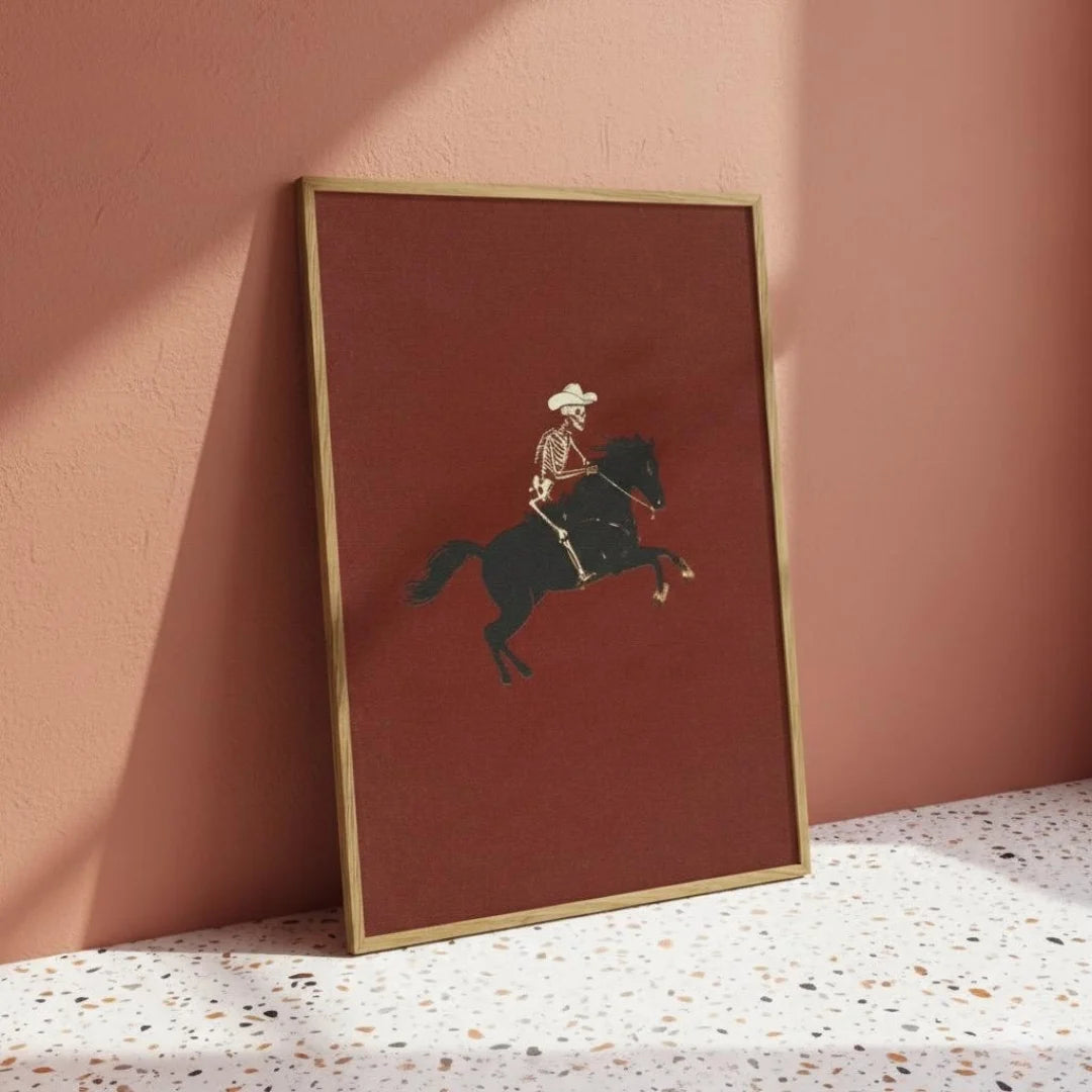 Framed artwork of a cowboy on a horse against a pink wall.