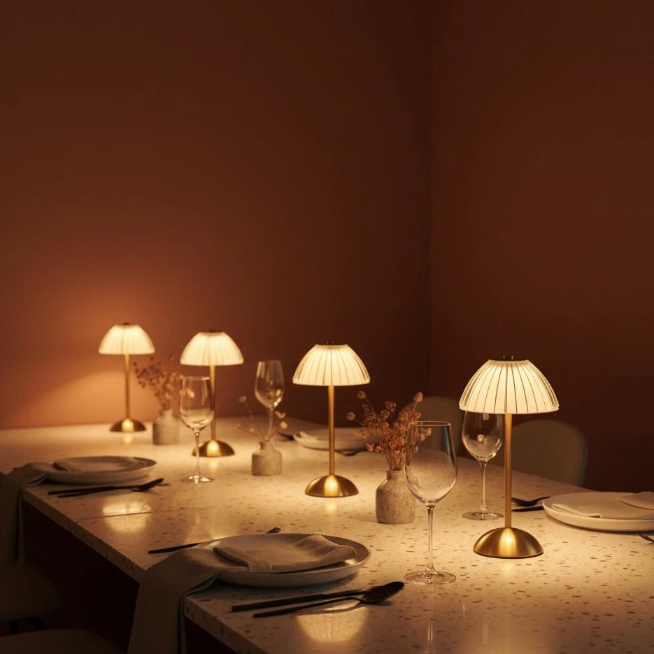 4 glass table lamps arranged on a table. Deep, salmon walls and plates, glasses and cutlery on the table.