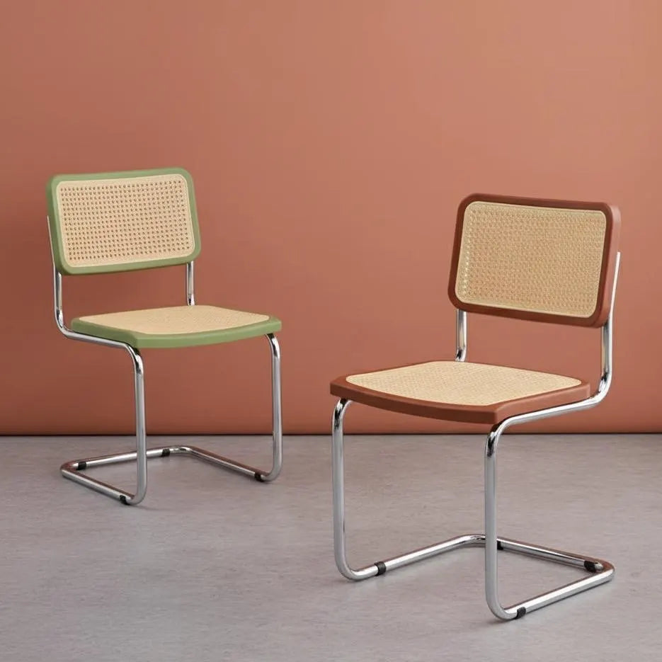 Two chairs with wicker backs and metal frames on a plain background