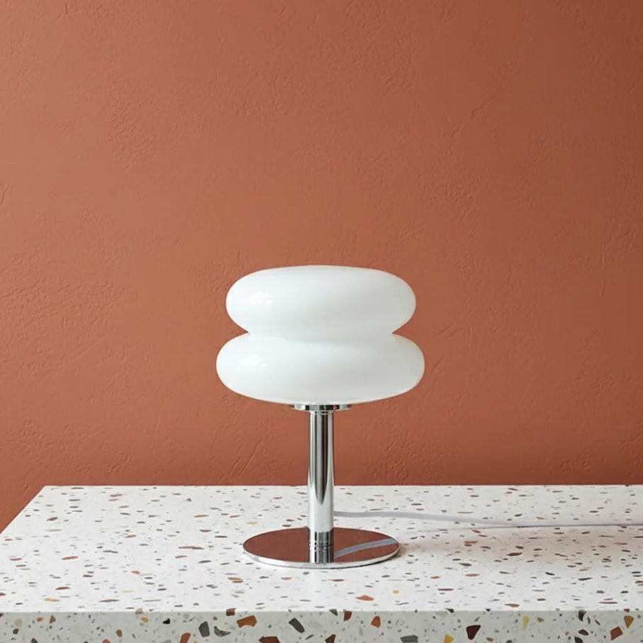 Modern table lamp with white glass shade on a terrazzo table against a brown wall