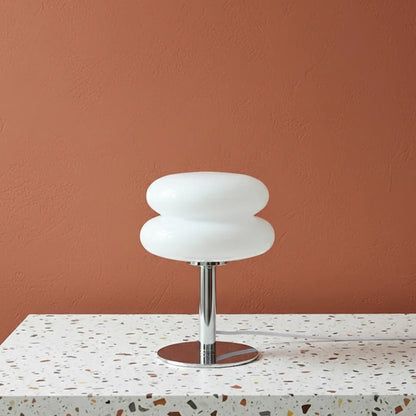 Modern table lamp with white glass shade on a terrazzo table against a brown wall